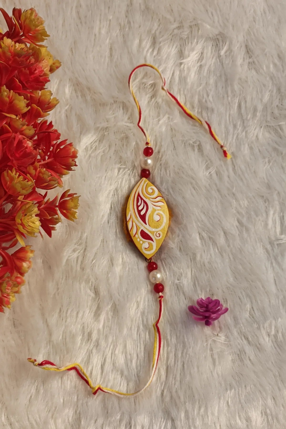 Close-up of the red and white paisley motif on a yellow terracotta rakhi