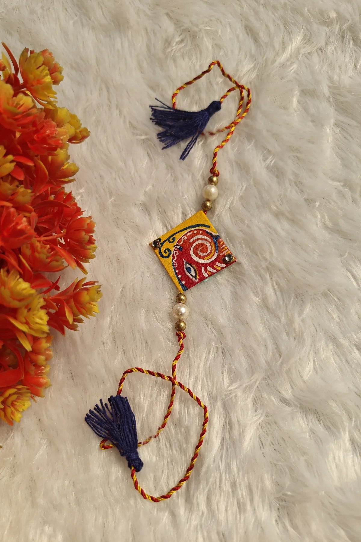 Close-up of the hand-painted red and white Pattachitra motif on a fabric rakhi