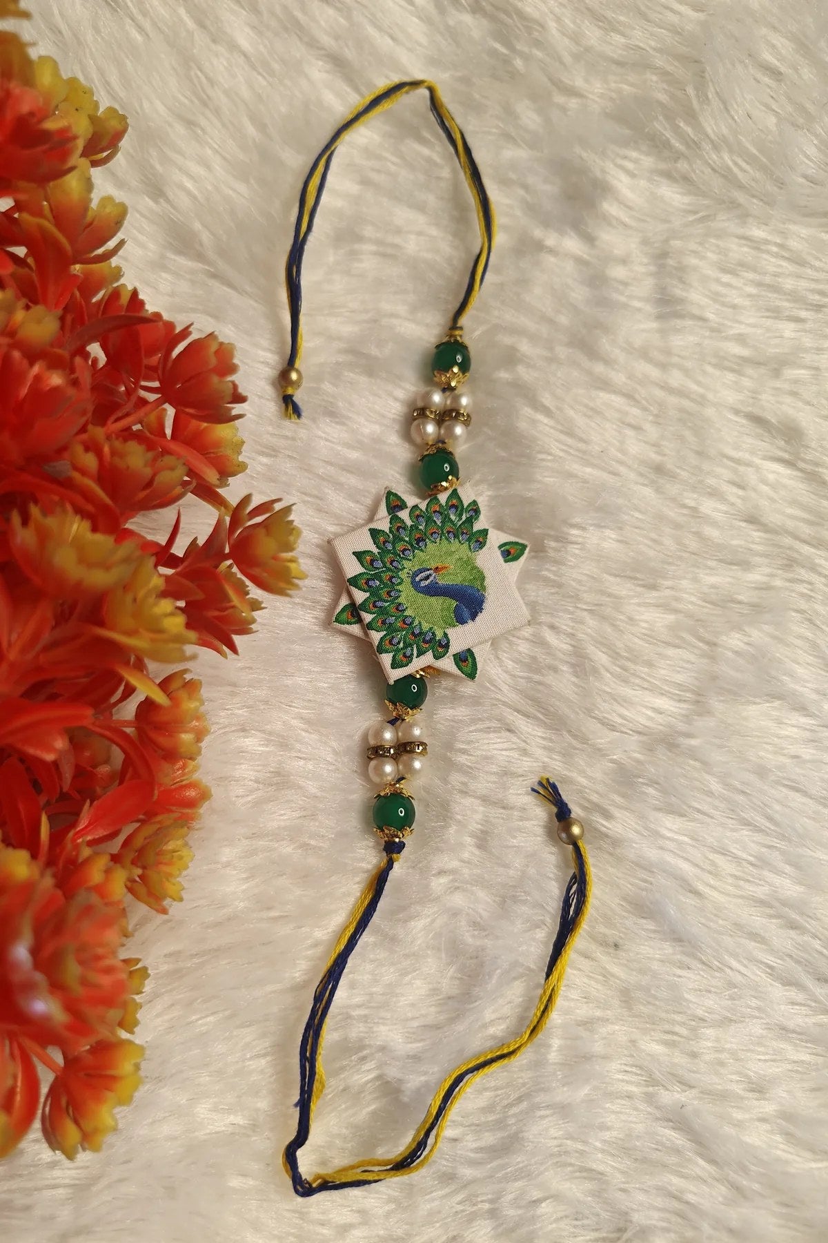 Close-up of the hand-painted peacock motif on a star-shaped fabric rakhi