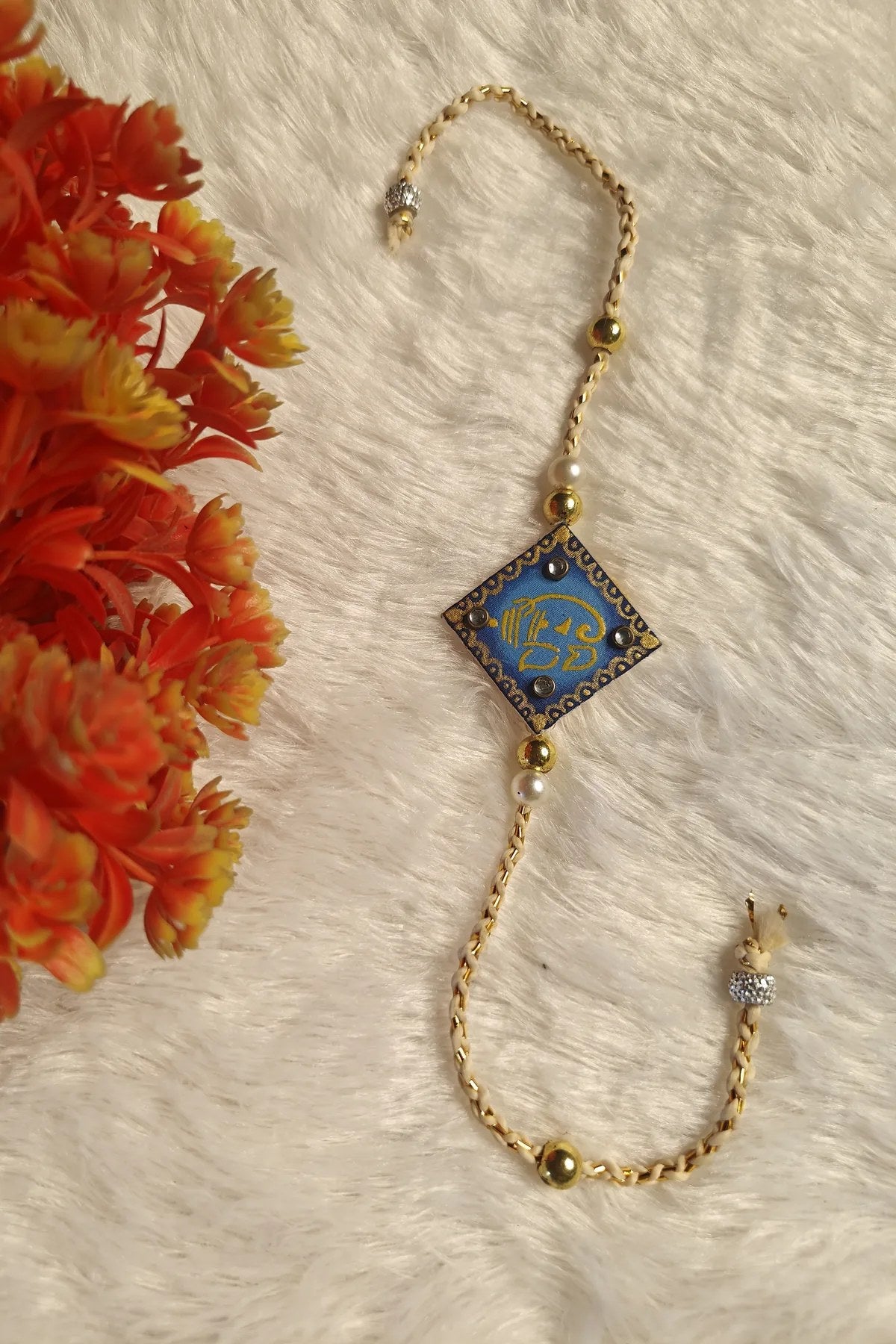 Close-up of the golden Ganesha motif on a blue fabric rakhi