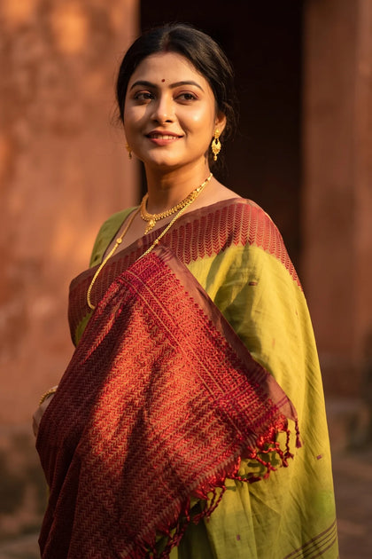 Noyontara handloom cotton saree in Mehendi Green with Maroon Kajur Chhari border, close-up portrait with gold jewellery