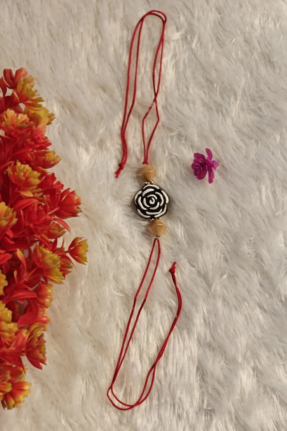 Close-up of the hand-carved black and white rose terracotta bead rakhi