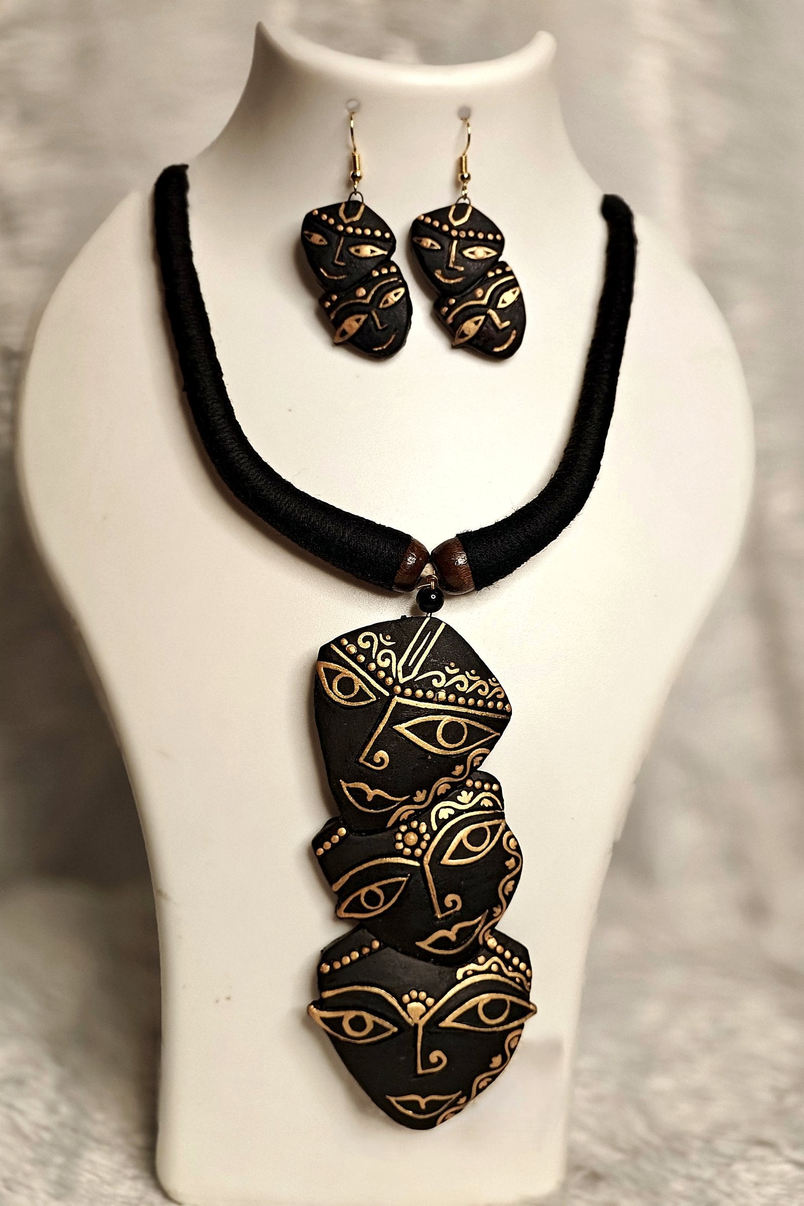 Close-up of hand-painted gold Durga Mukhosh terracotta pendant on black thread necklace - Bong Trendz