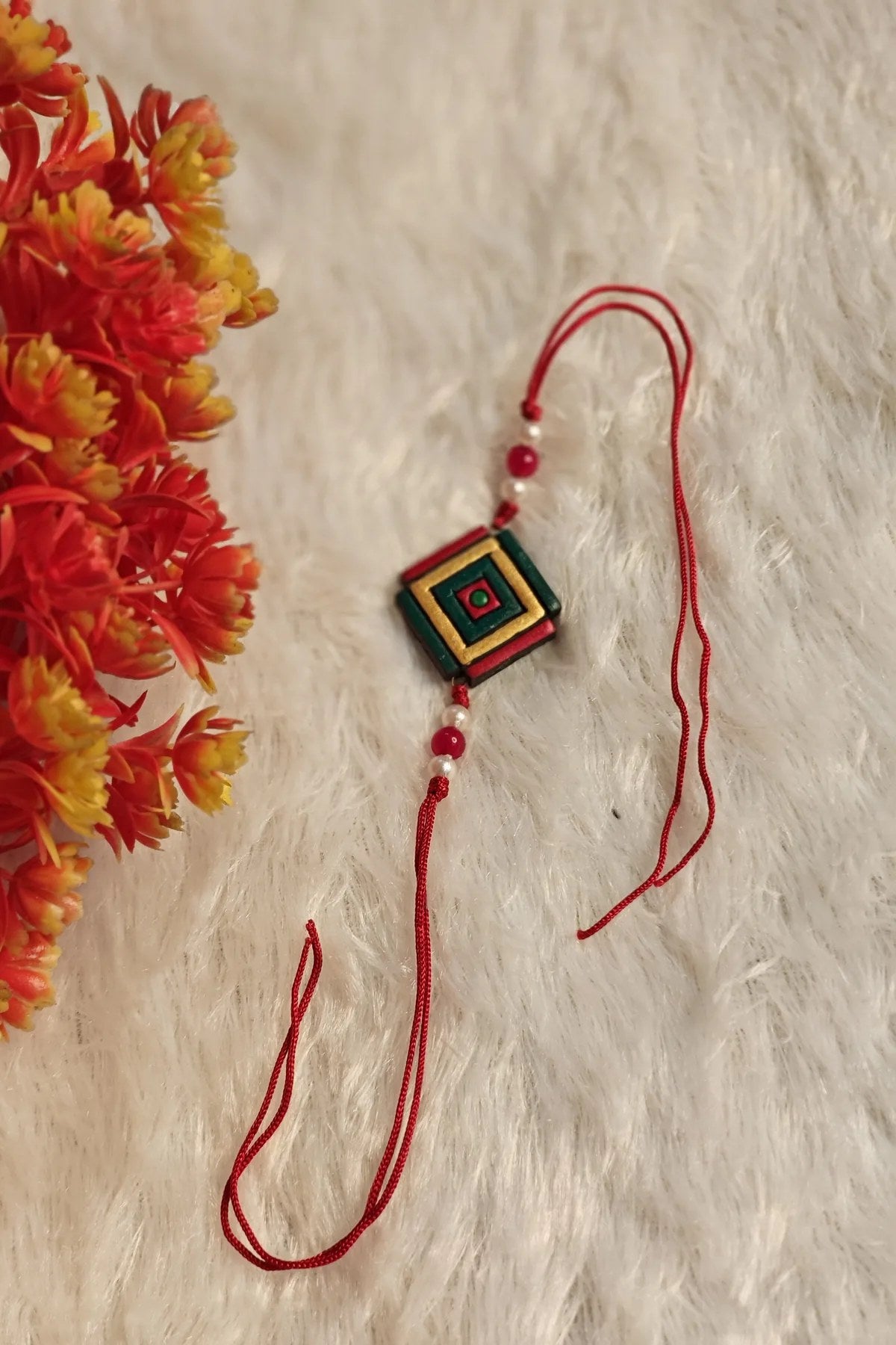 Close-up of the concentric green, gold and red geometric terracotta rakhi