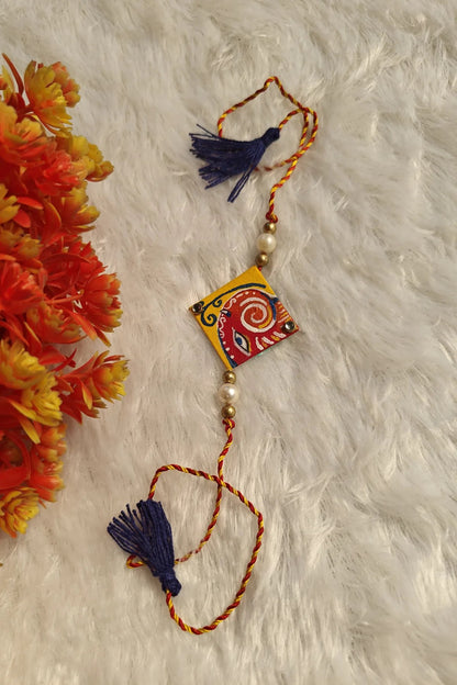 Close-up of the hand-painted red and white Pattachitra motif on a fabric rakhi