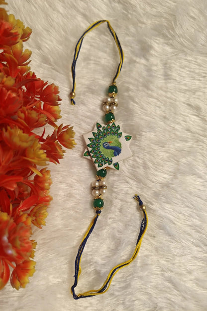 Close-up of the hand-painted peacock motif on a star-shaped fabric rakhi