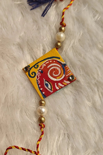 Hand-painted Pattachitra fabric rakhi with blue tassels and pearls – Bengal folk-art Raksha Bandhan thread by Bong Trendz