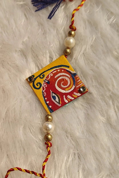 Hand-painted Pattachitra fabric rakhi with blue tassels and pearls – Bengal folk-art Raksha Bandhan thread by Bong Trendz