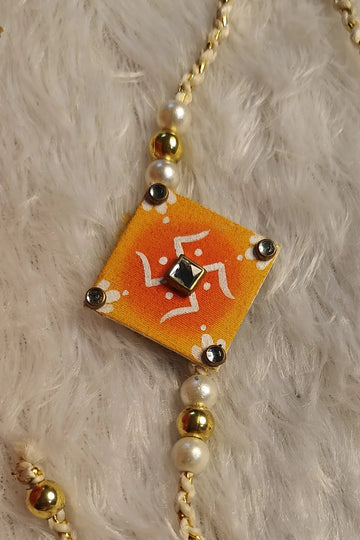 Hand-painted alpona fabric rakhi in orange with kundan and pearls – Bengal folk-art Raksha Bandhan thread by Bong Trendz