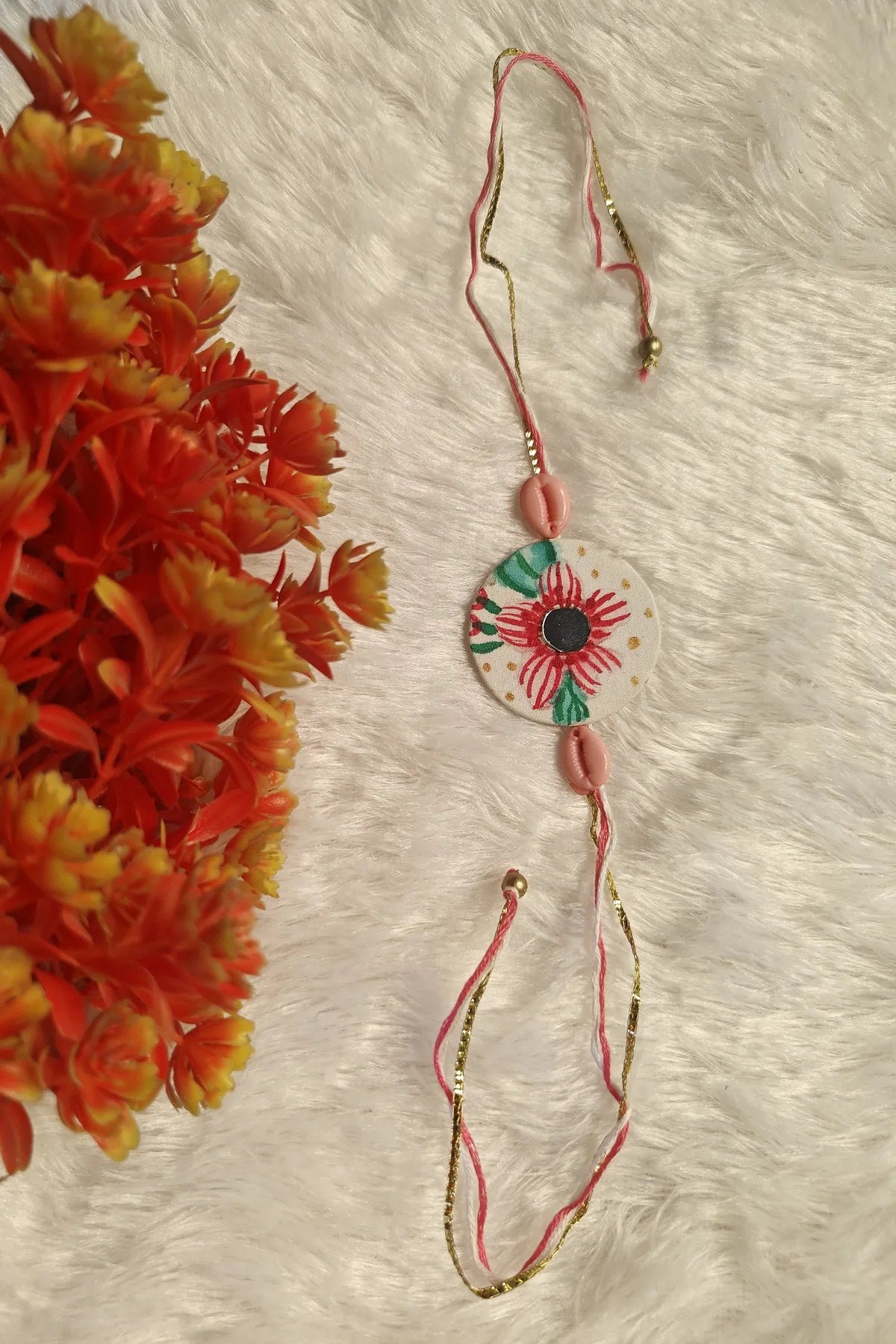 Close-up of the hand-painted red bloom on an ivory fabric rakhi