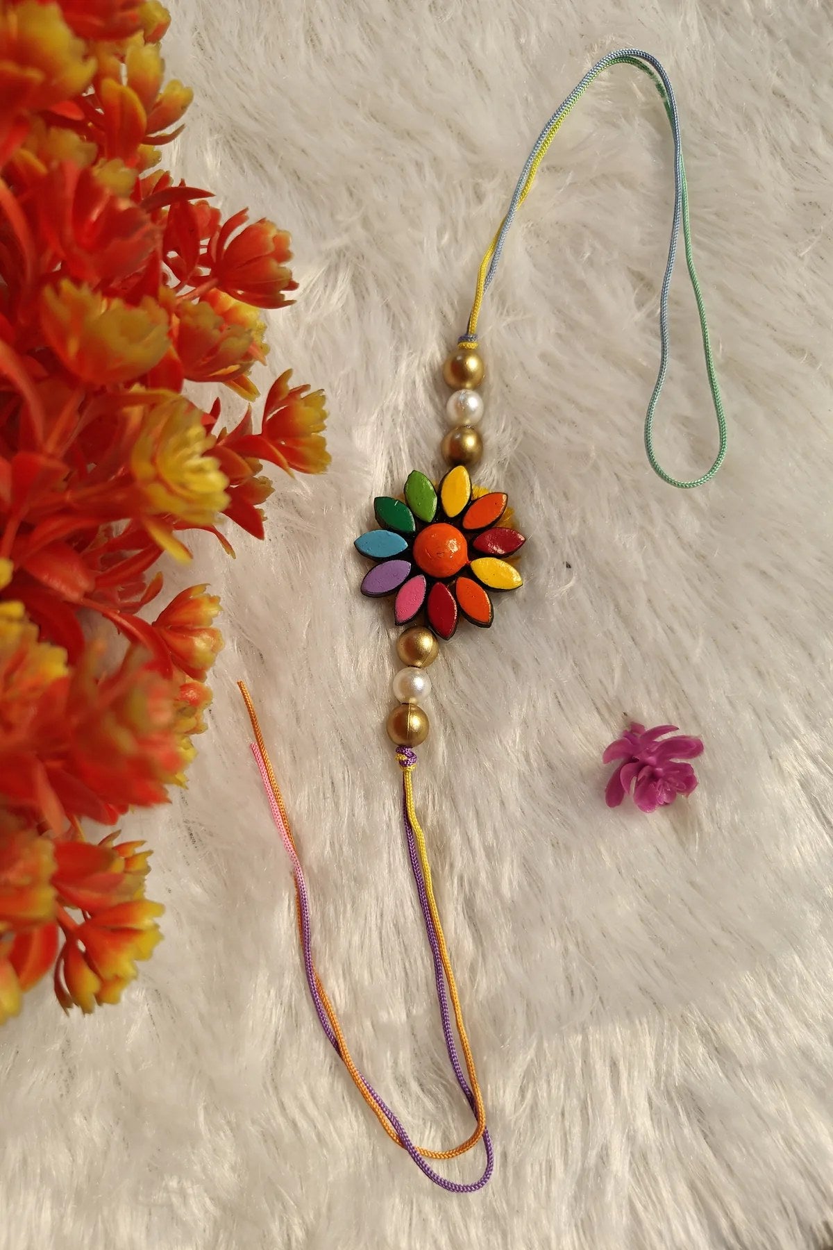 Close-up of the hand-painted rainbow terracotta flower rakhi