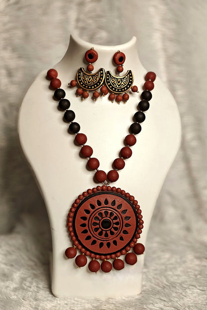 Close-up of carved terracotta wheel medallion pendant with gold-accented crescent earrings - Bong Trendz