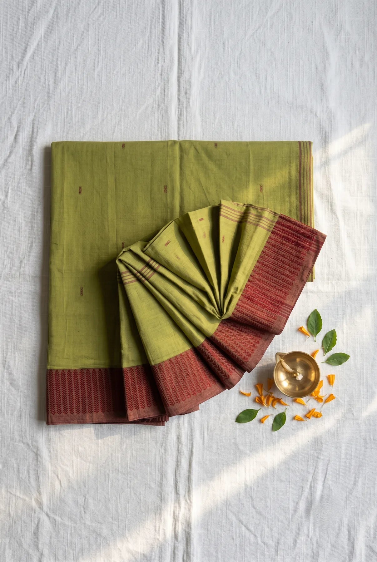 Noyontara Mehendi Green pure cotton saree with Maroon Kajur Chhari border, folded flat-lay with pallu fan