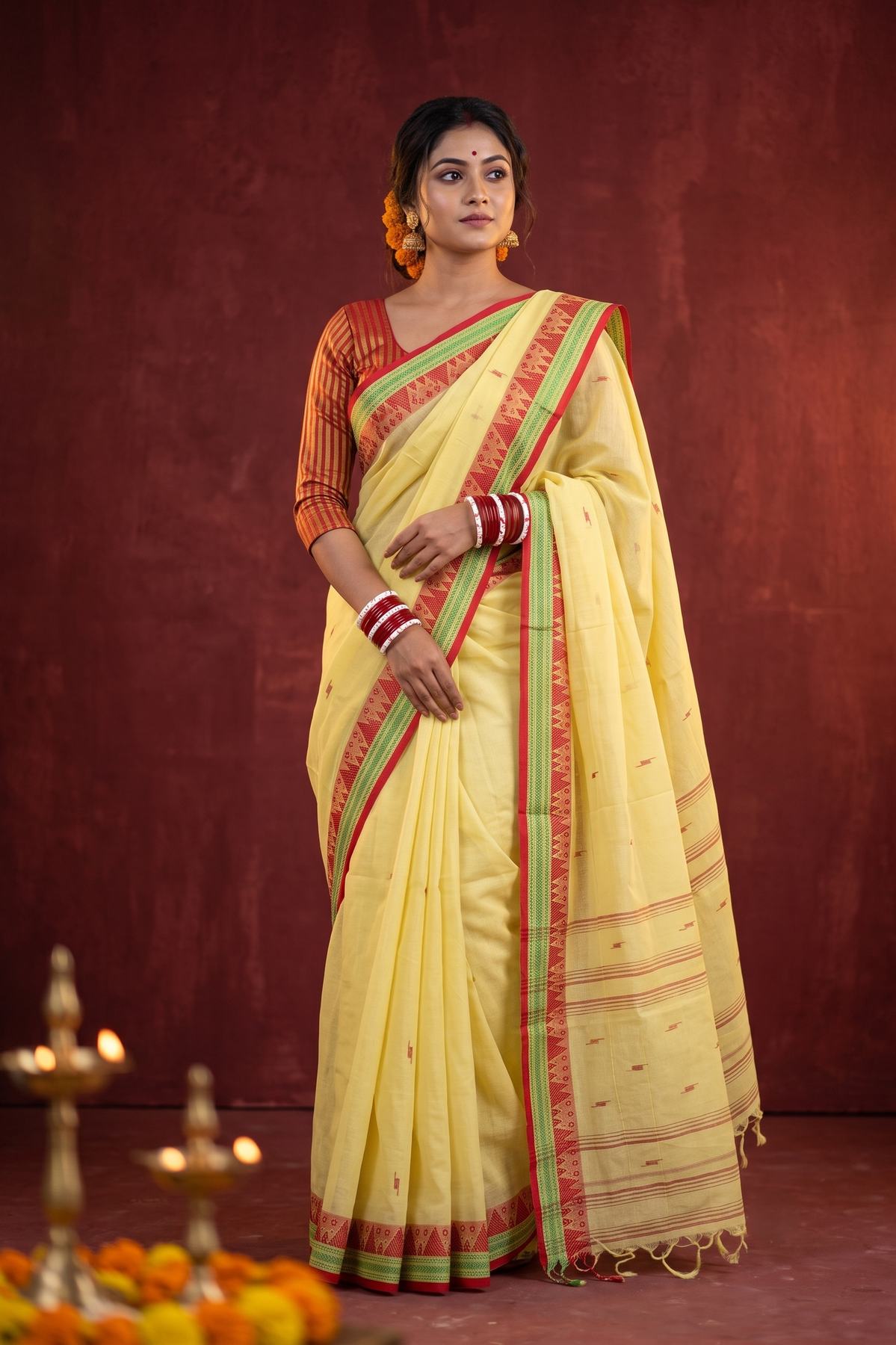 Konika yellow Shantipur handloom cotton saree draped front view with red and green pallu border