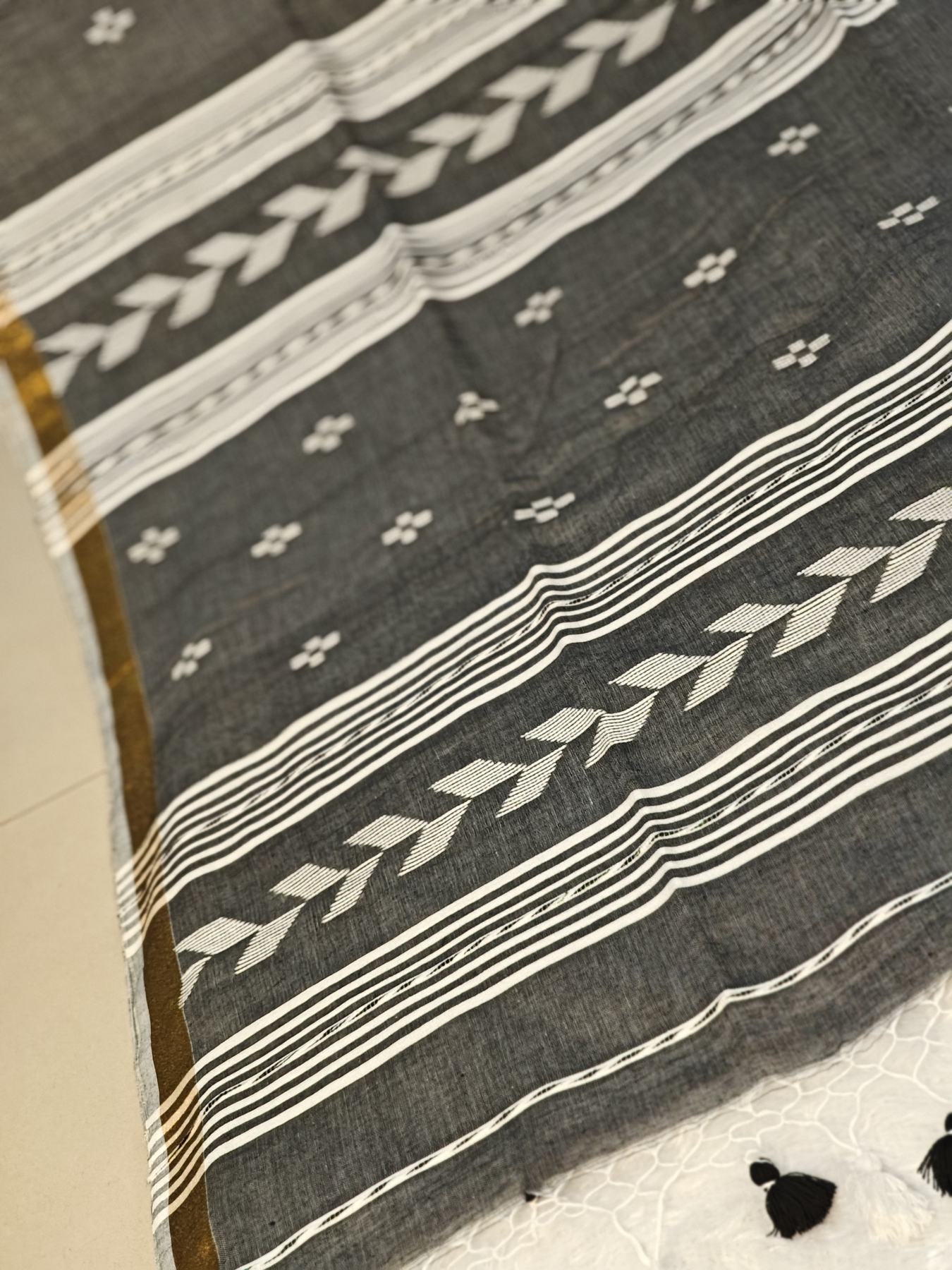 Close-up of the grey Tirlata saree's arrow buti border with pallu tassels