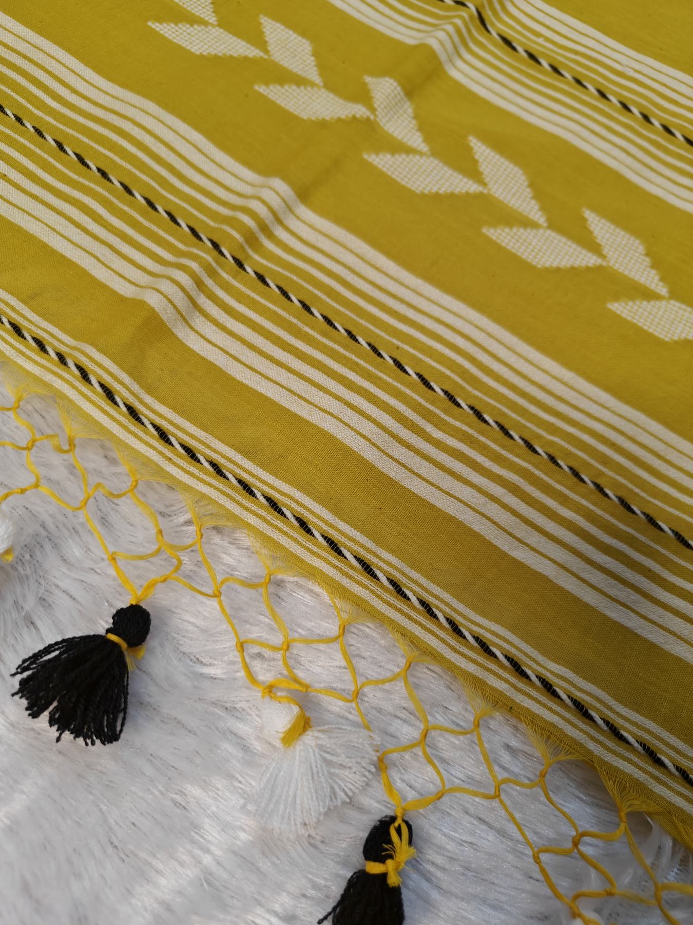 Close-up of the mustard Tirlata saree's pallu tassels and arrow buti border