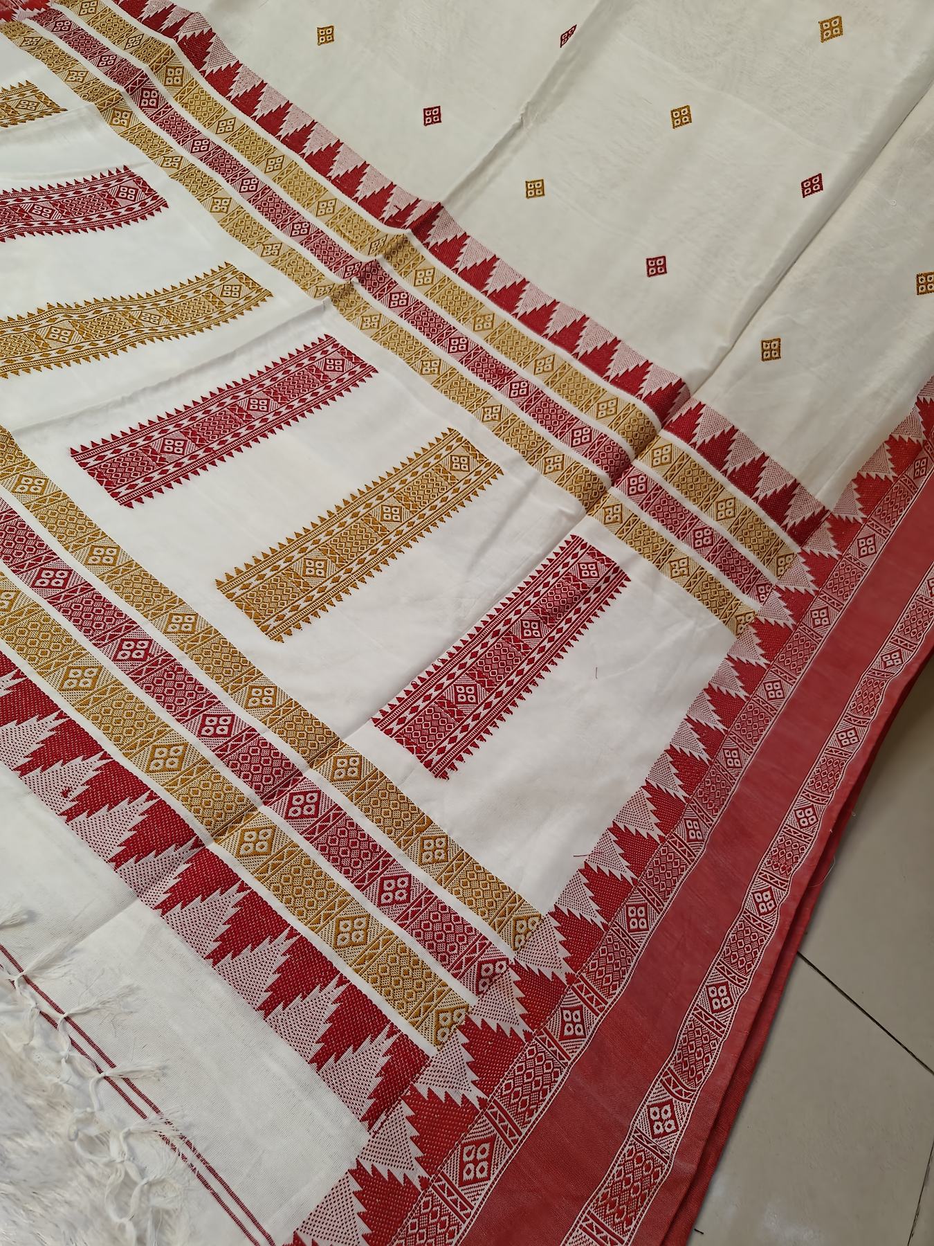 Close-up of the Ushoshi saree's red temple-tooth pallu border with diamond buti weave on off-white handwoven cotton